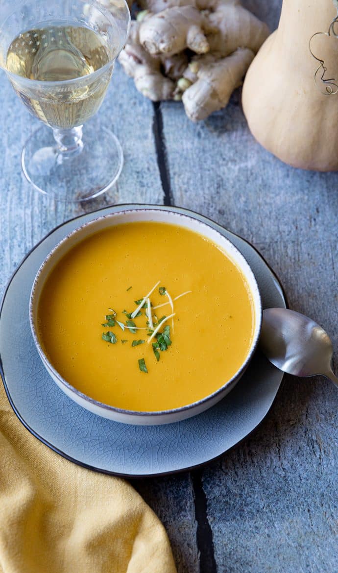 Recette de soupe de butternut au gingembre servie avec des filaments de gingembre frais et du persil. 