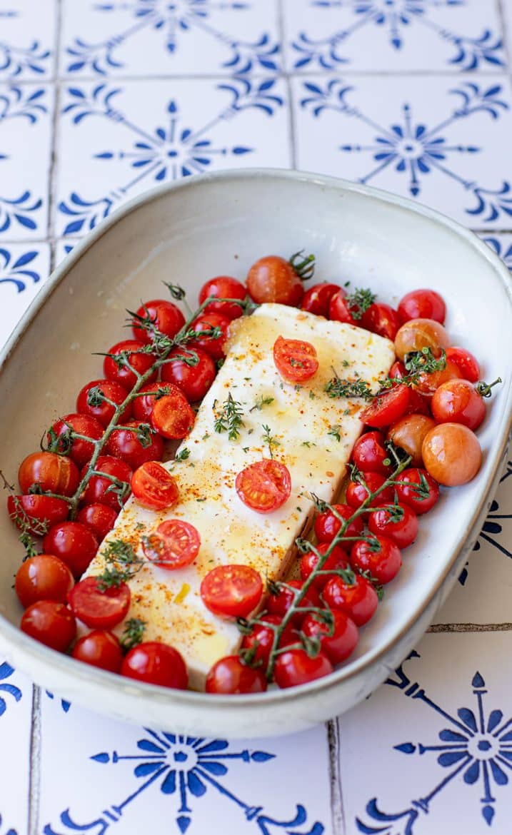 Préparation de la feta rôtie aux tomates cerises directement dans le plat à gratin.